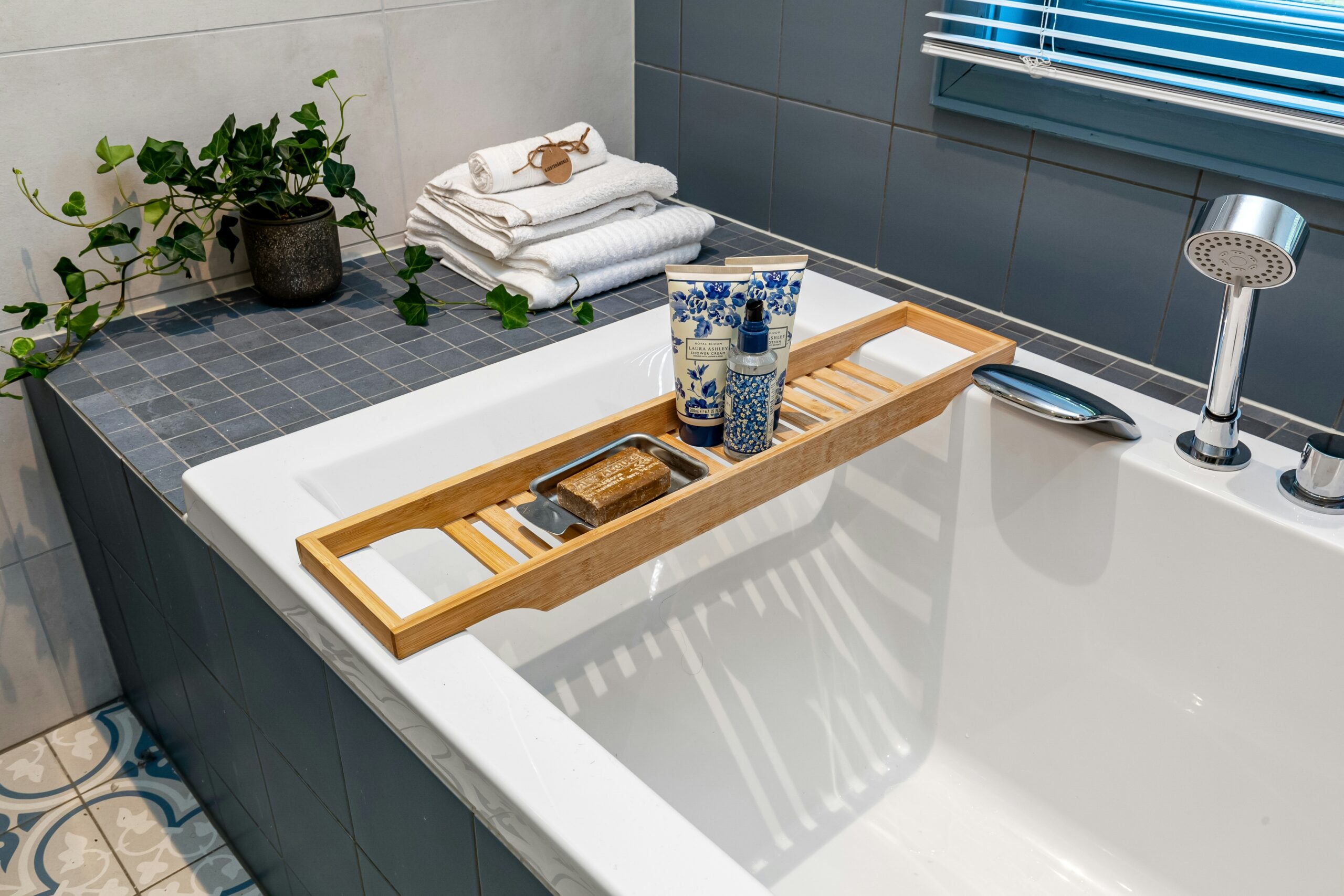 Selfcare Routine im Badezimmer mit warmer Badewanne, Handtüchern und einer schlichten Badewannenablage