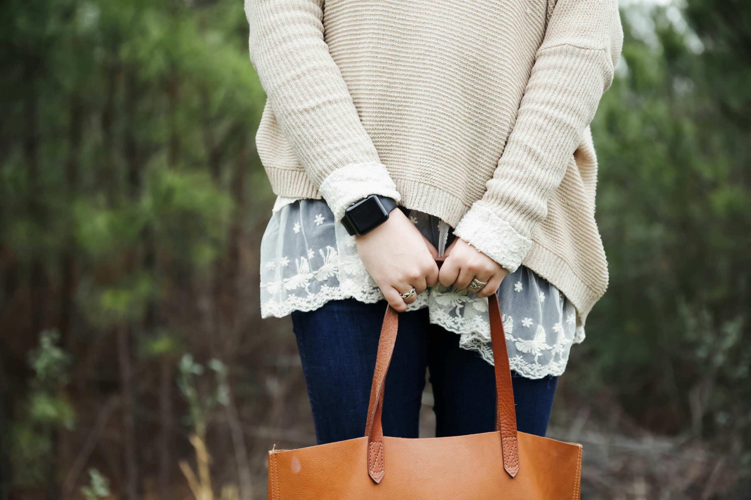 zeitlose Basics Frau – lässiges Outfit-Flatlay mit Jeans, Strickpullover, kariertem Schal und Alltagstasche