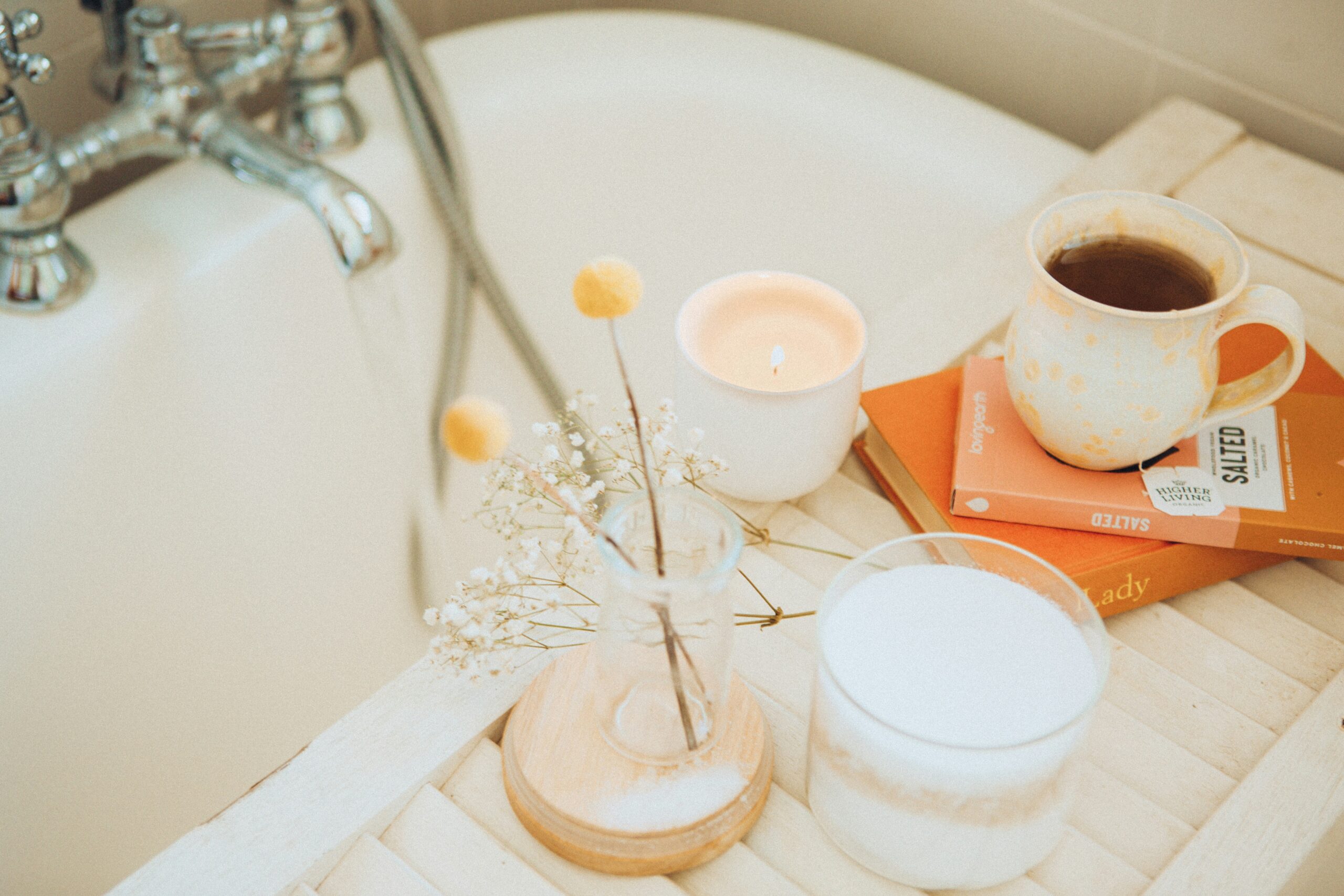 Selfcare Routine mit hellen Handtüchern, Pflegeprodukten, Kerze und natürlichen Spa-Accessoires auf einem Badezimmer-Flatlay